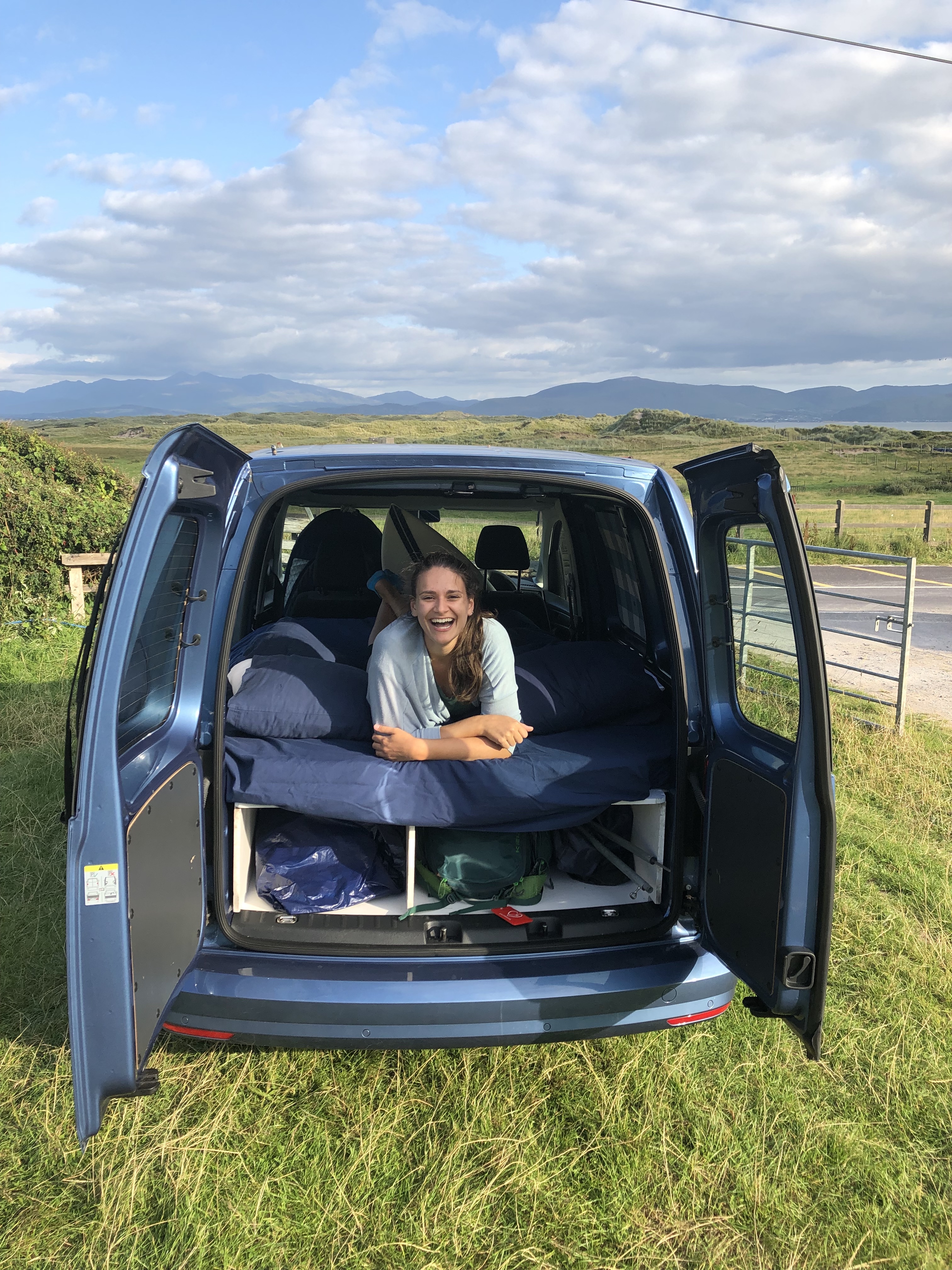 Nicola in a camper van smiling with mountains in the background